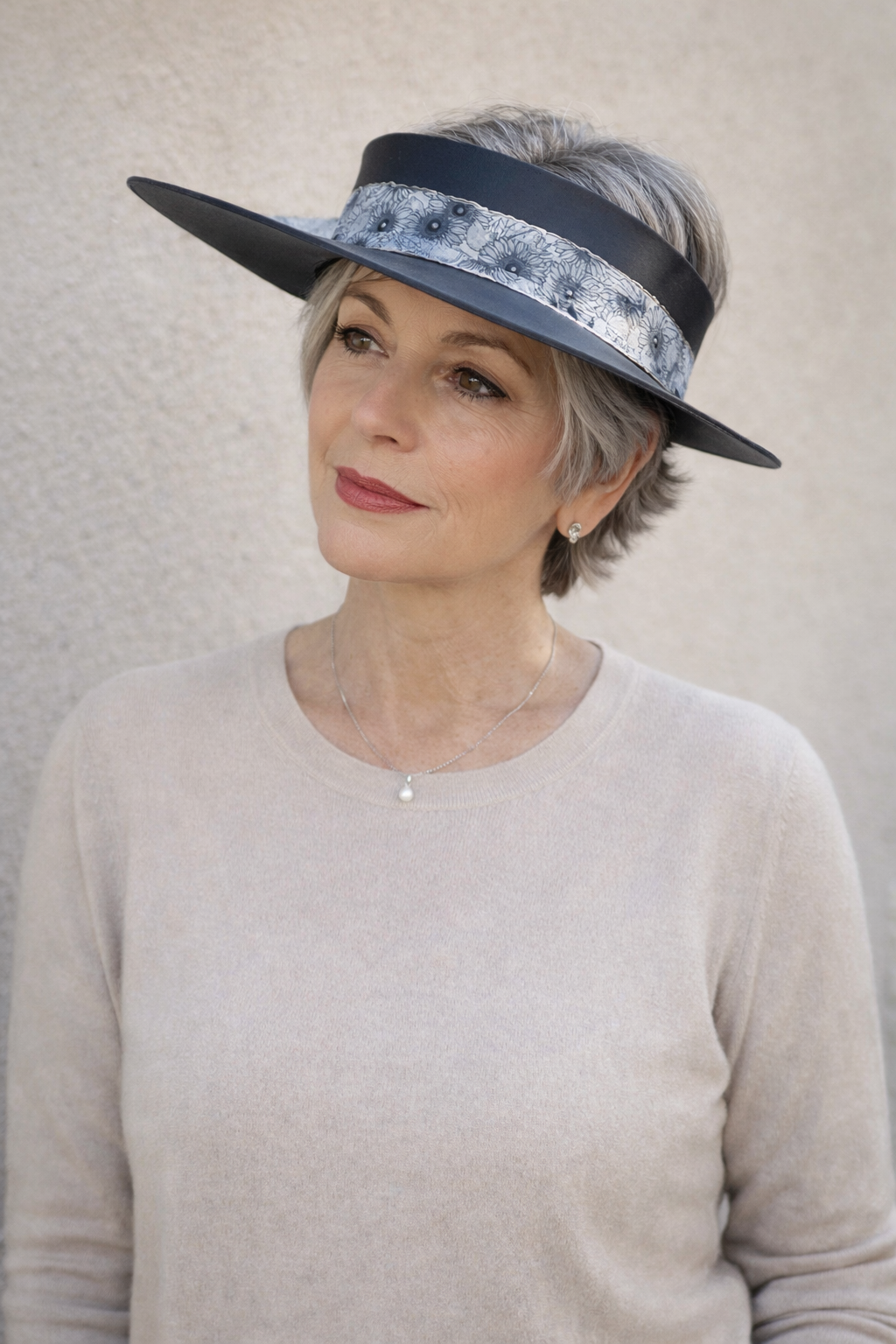 Woman wearing a wide-brimmed hat with a decorative band against a neutral background