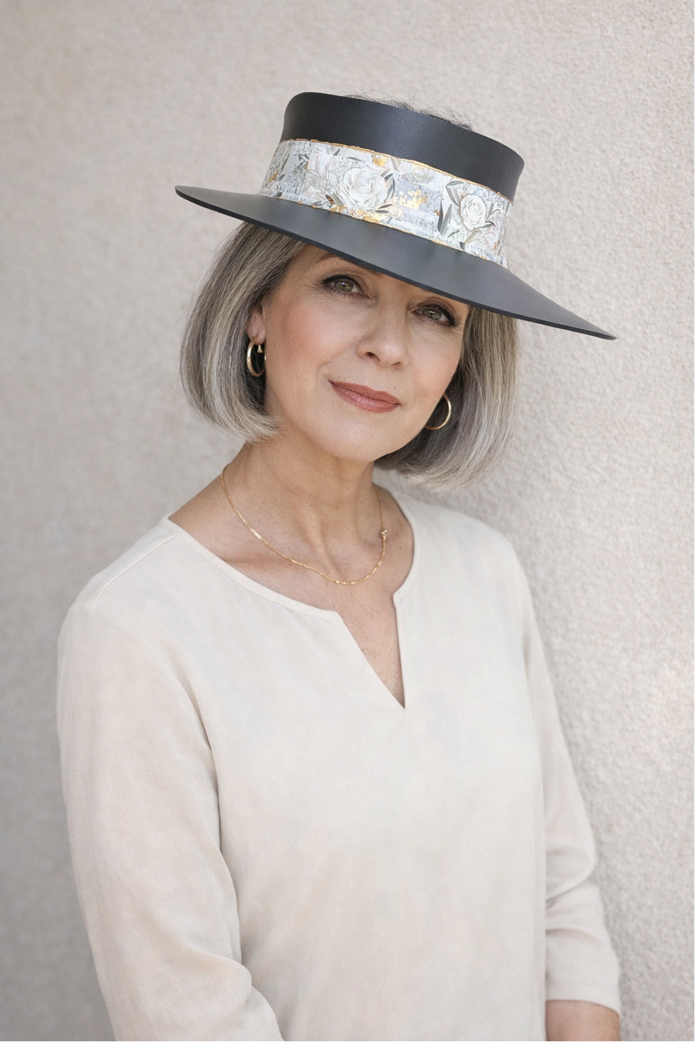 Woman wearing a stylish hat with a patterned band against a plain background
