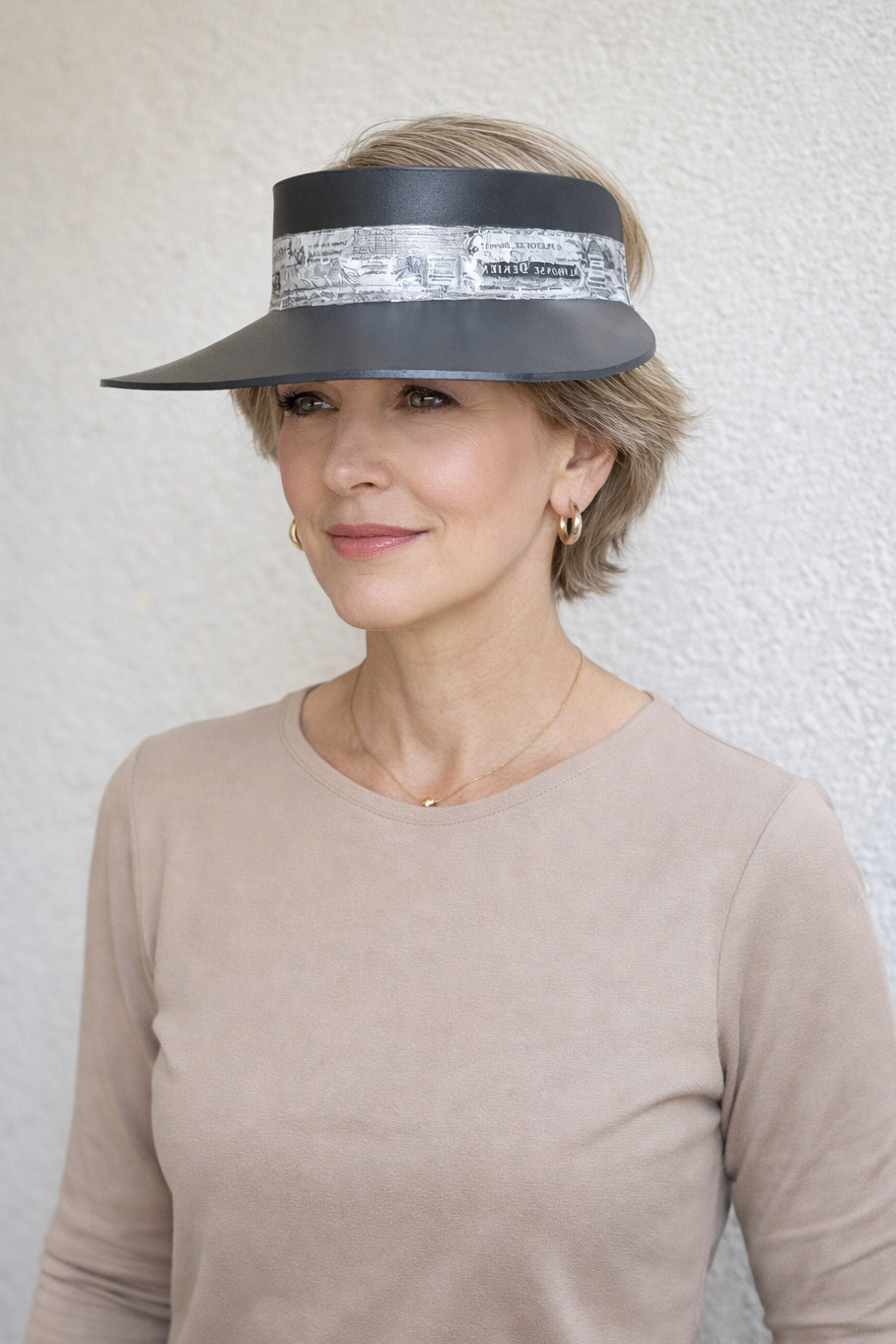 Woman wearing a wide-brimmed hat with a decorative band against a plain background
