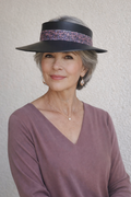 Woman wearing a wide-brimmed hat with a patterned band against a plain background