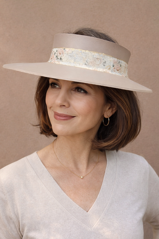 Woman wearing a wide-brimmed hat with decorative band against a beige background