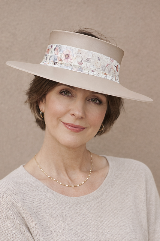 Woman wearing a wide-brimmed hat with floral band against a beige background
