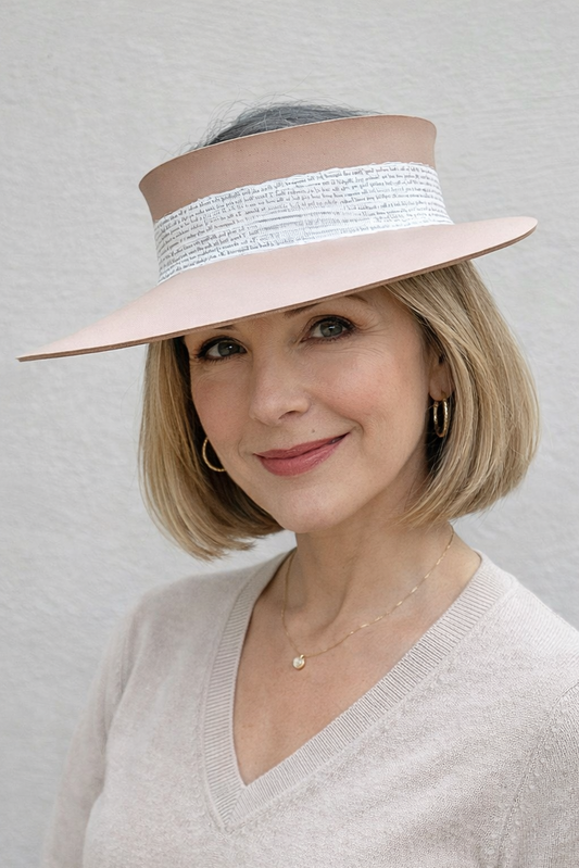 Woman wearing a beige visor hat with a white band against a gray background