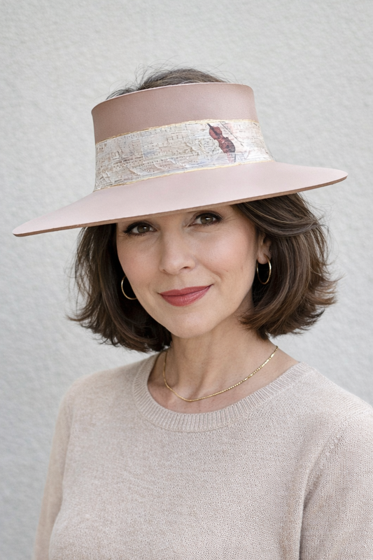 Woman wearing a pink hat with a feather against a plain background