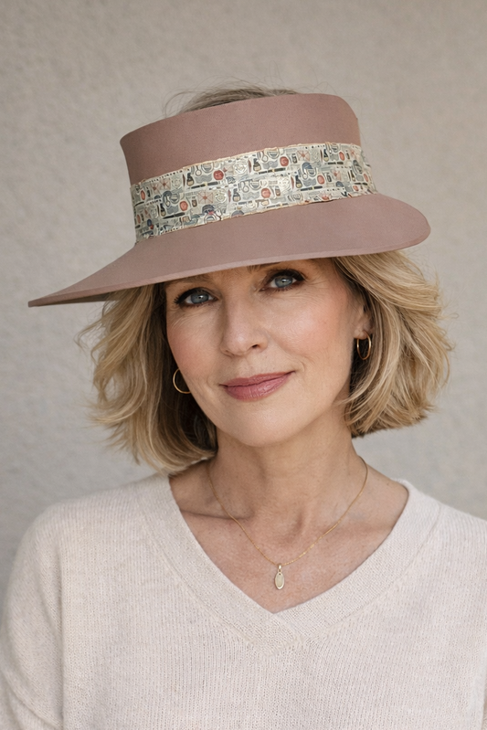 Woman wearing a beige hat with a floral band against a neutral background
