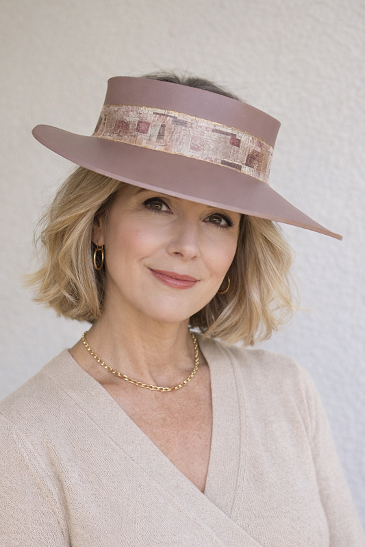 Woman wearing a wide-brimmed hat with a decorative band against a plain background