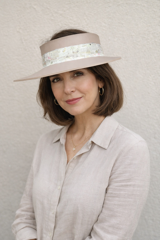 Woman wearing a beige visor with floral details against a plain background