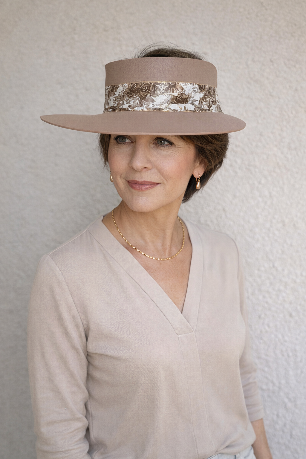 Woman wearing a wide-brimmed hat with decorative band against a plain background