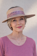 Woman wearing a wide-brimmed hat with a decorative band against a plain background