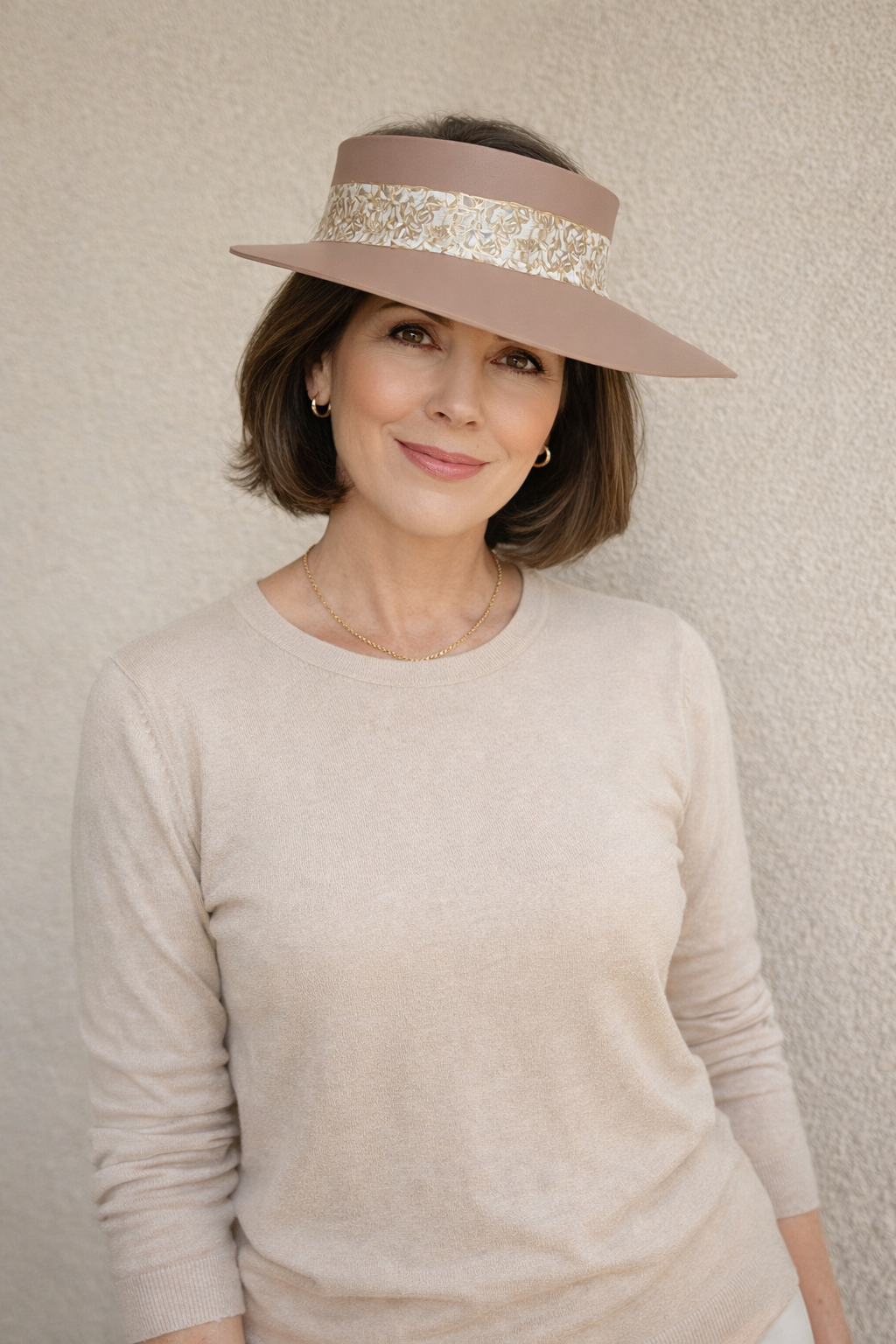 Woman wearing a beige visor hat against a neutral background