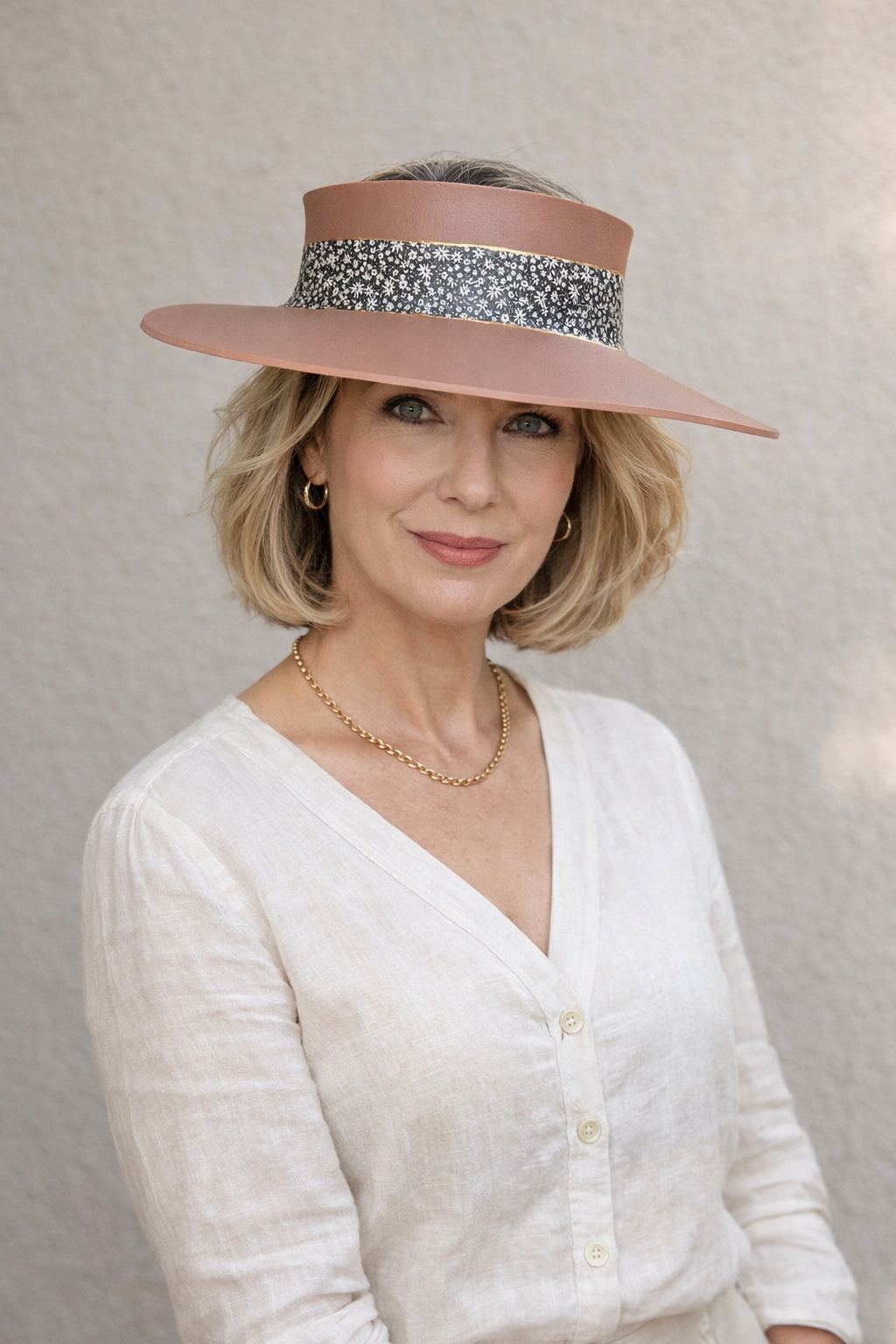 Woman wearing a wide-brimmed hat with a floral band against a neutral background
