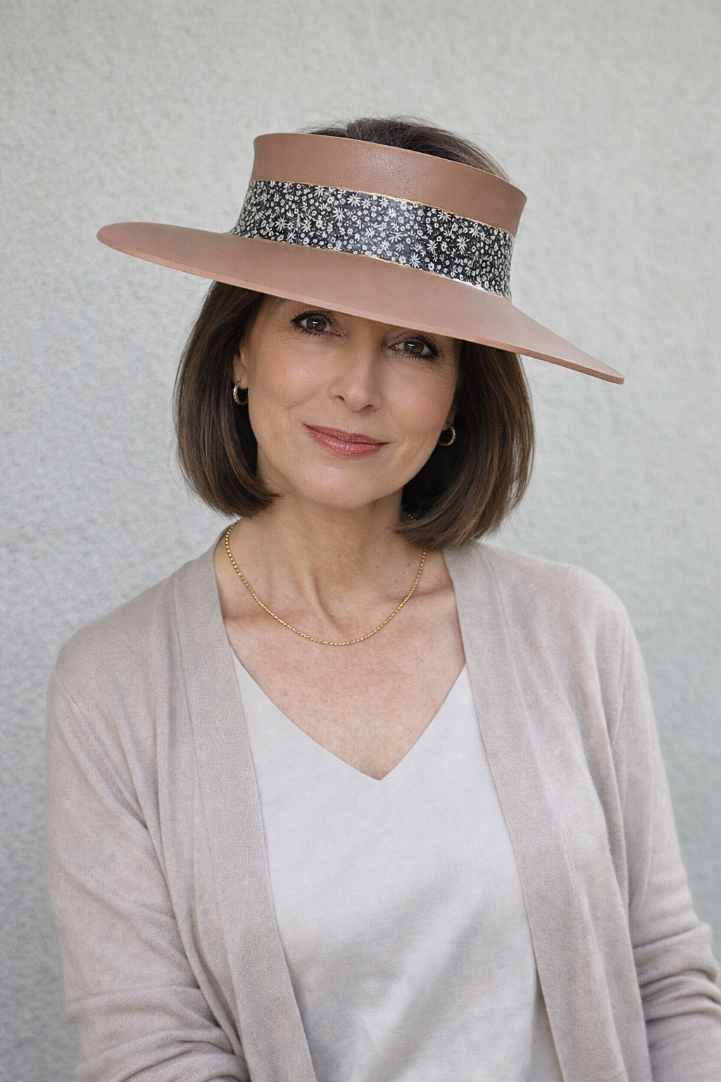 Woman wearing a wide-brimmed hat with a decorative band against a plain background