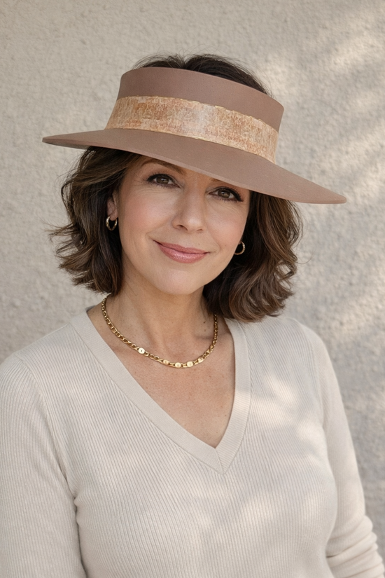 Woman wearing a beige visor hat and light sweater against a neutral background