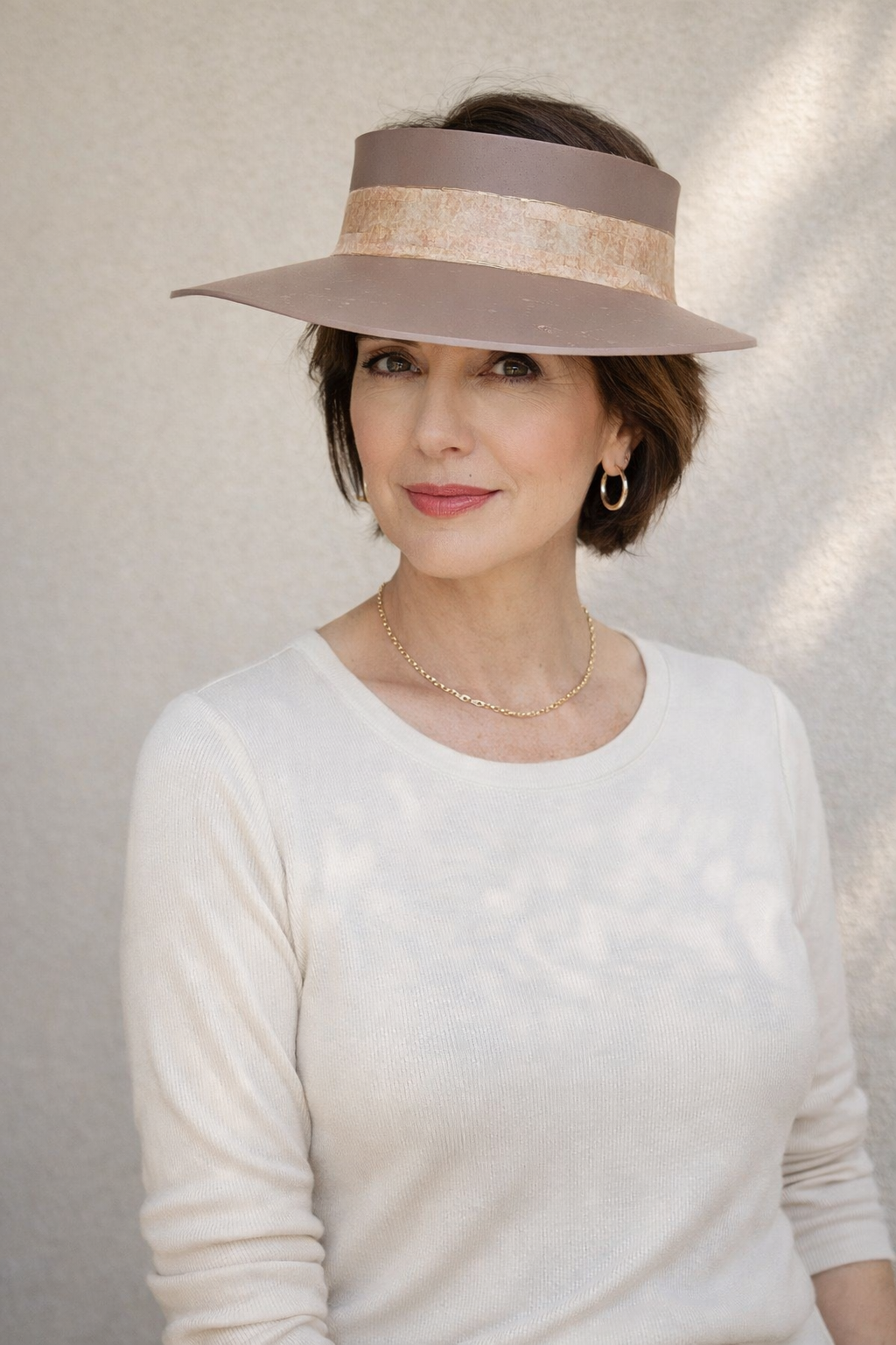 Woman wearing a wide-brimmed hat with a neutral background