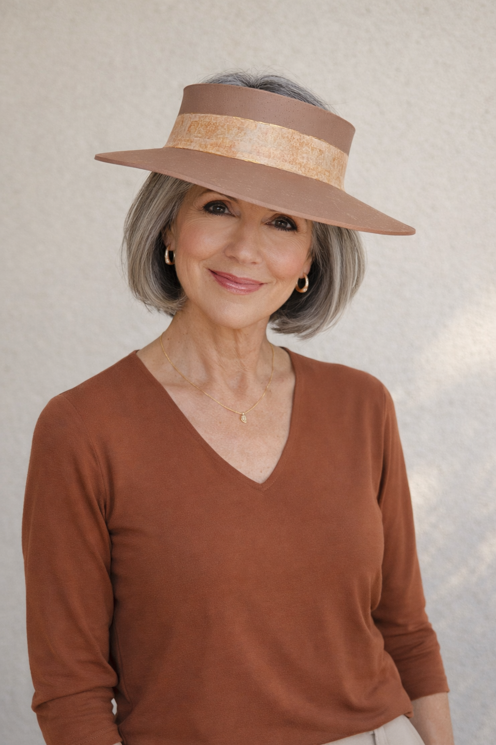 Woman wearing a brown visor and matching sweater against a neutral background