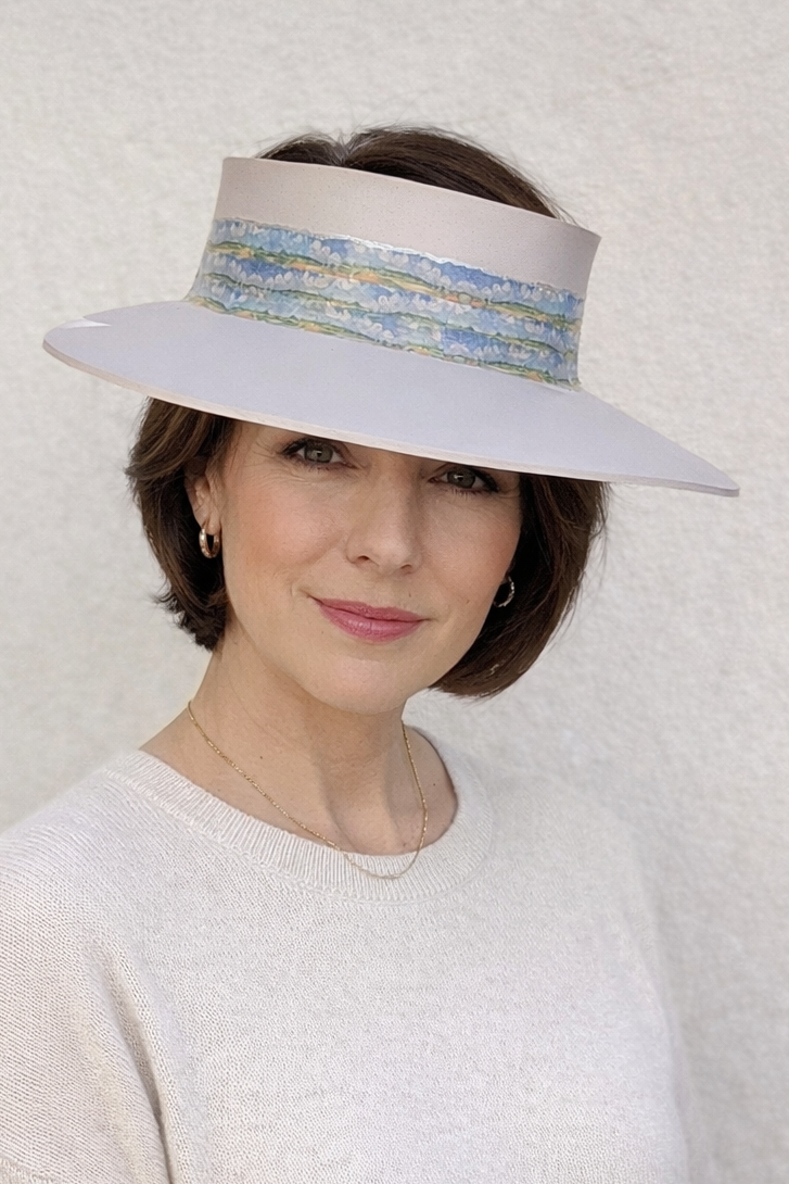 Woman wearing a wide-brimmed hat with decorative band against a plain background