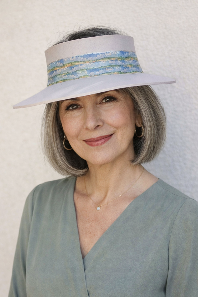 Woman wearing a light blue dress and sun visor against a white background