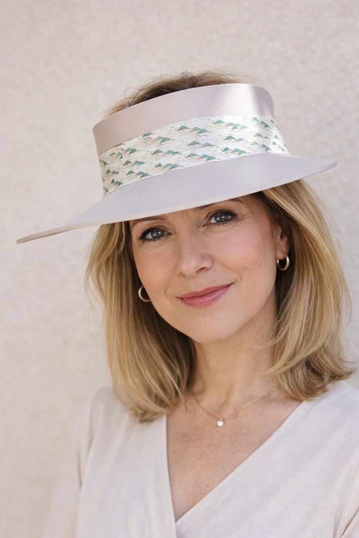 Woman wearing a white visor with a patterned band against a beige background