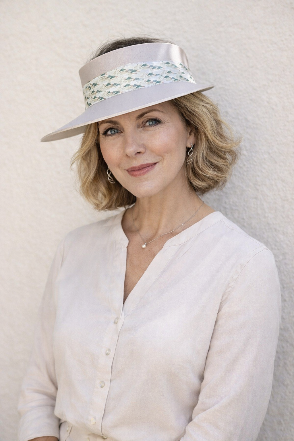 Woman wearing a white visor and light-colored outfit against a neutral background