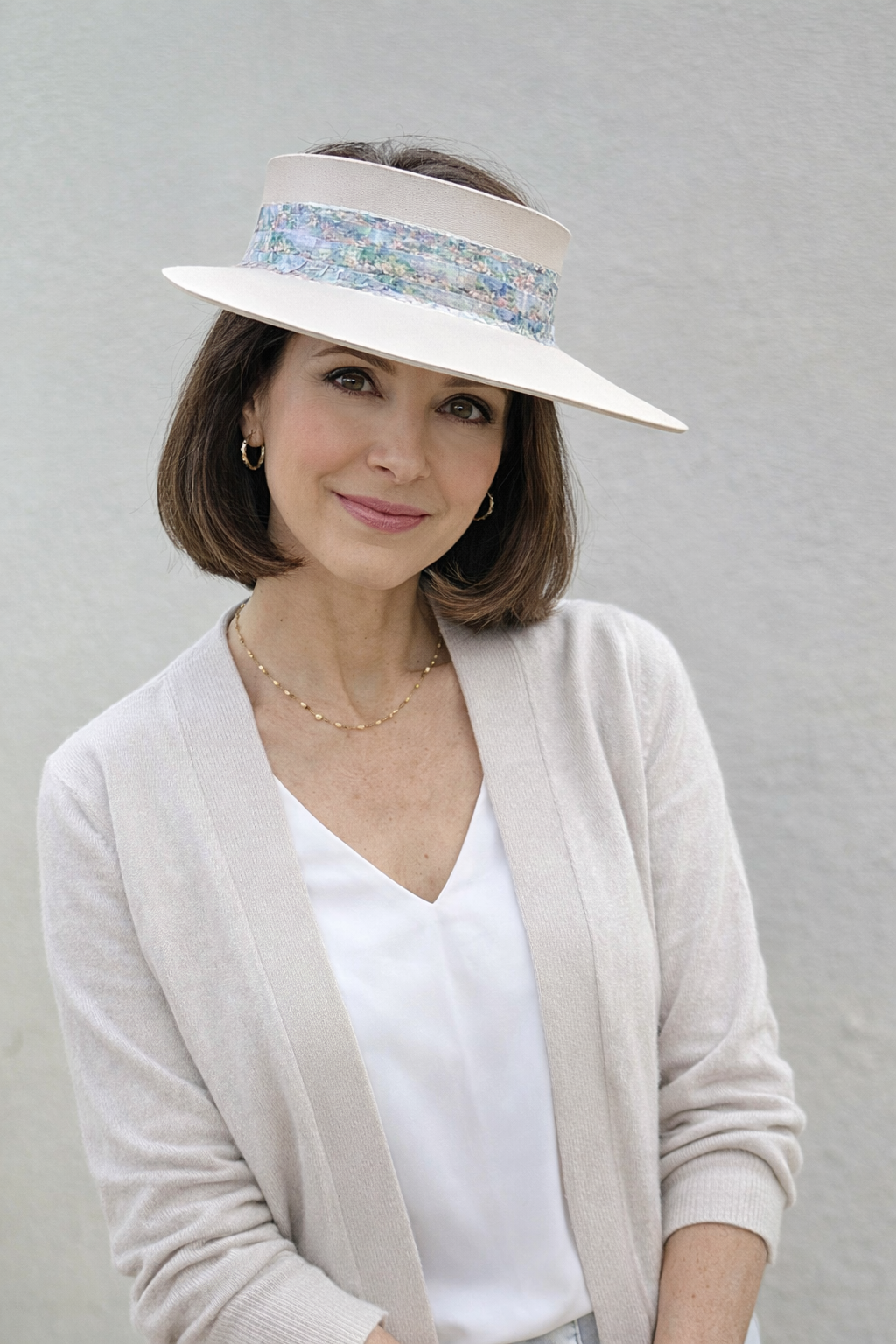 Woman wearing a white visor with a patterned band against a gray background