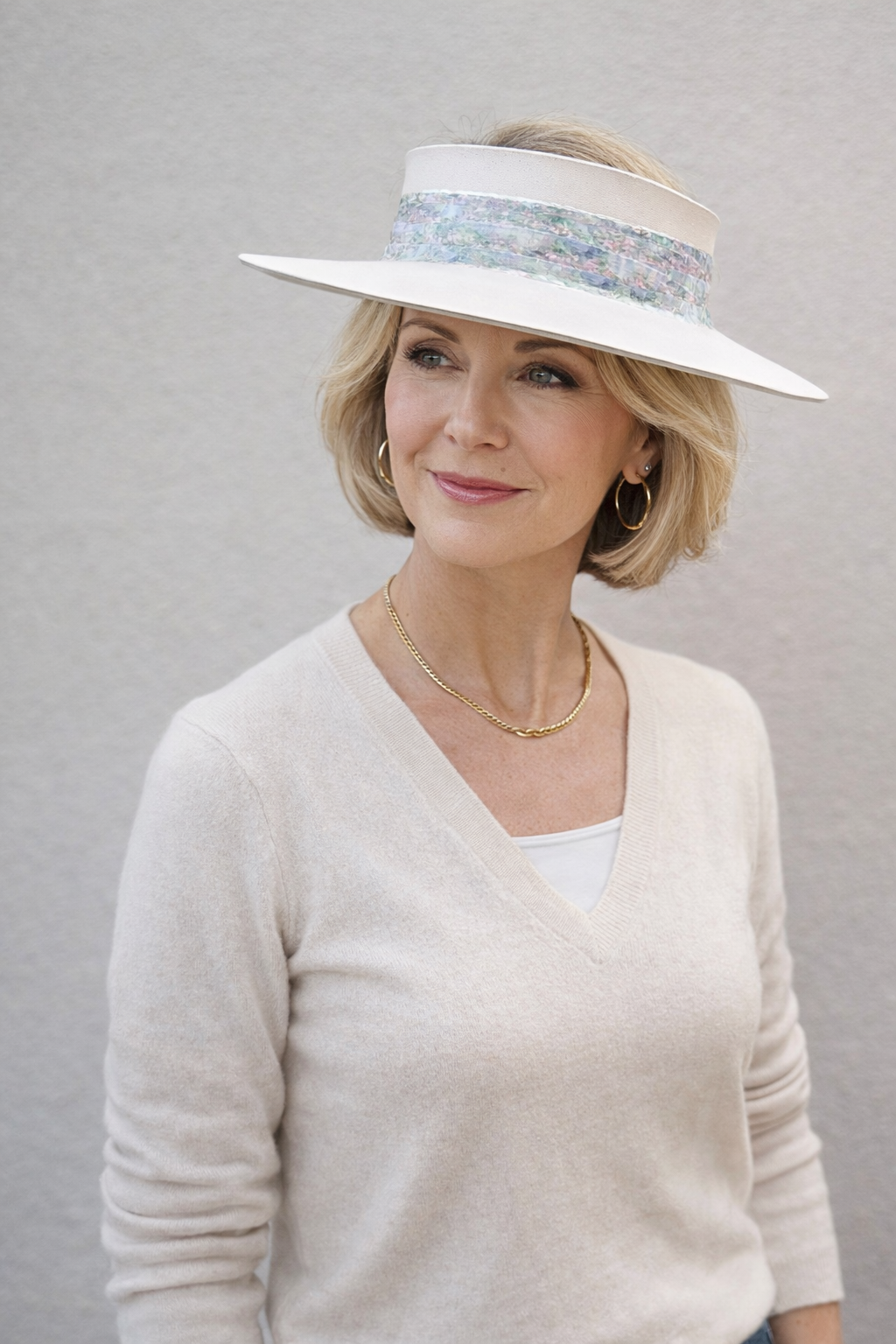 Woman wearing a white sun hat with a floral band against a gray background