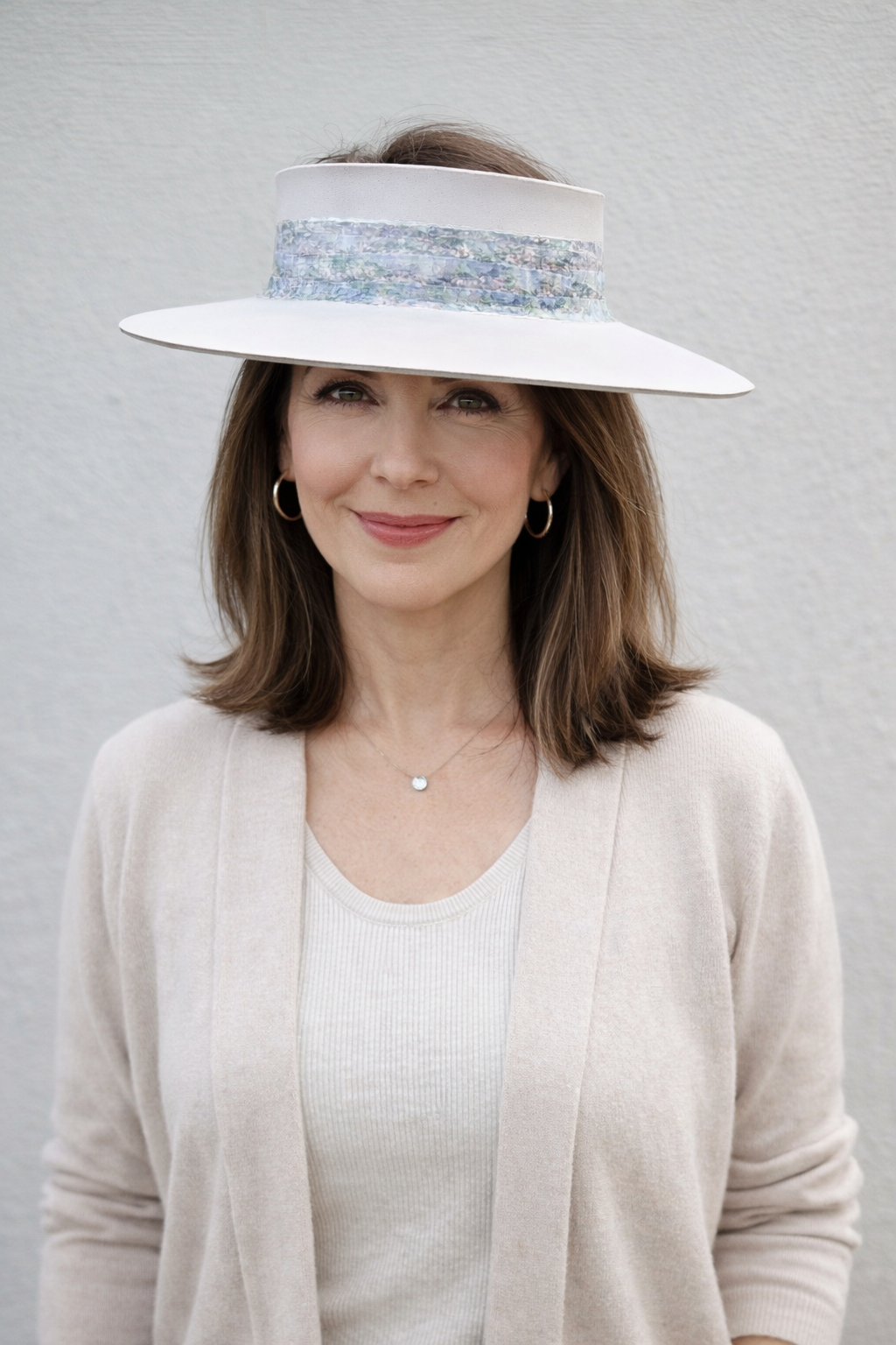 Woman wearing a wide-brimmed hat with a decorative band against a plain background