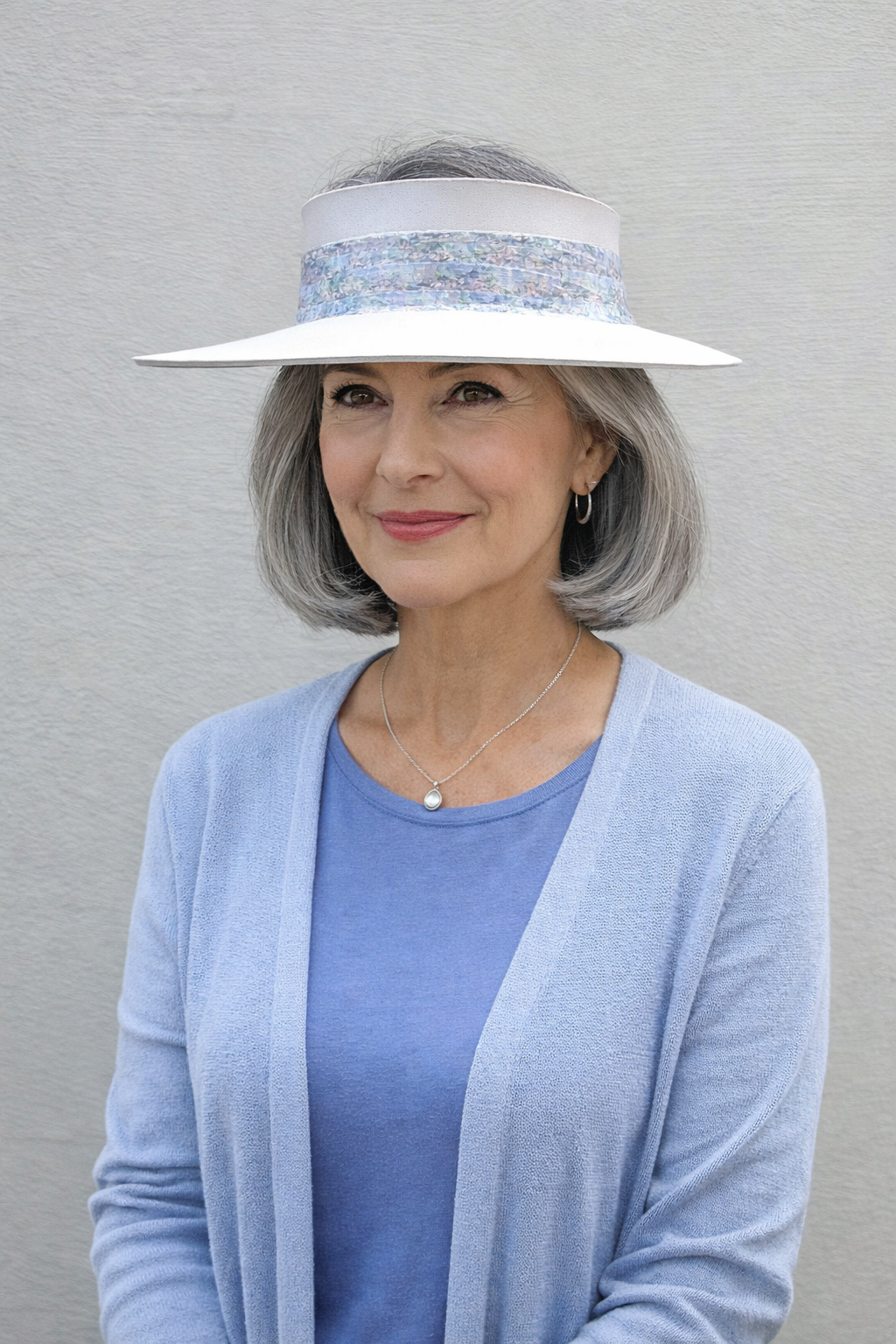 Woman wearing a wide-brimmed hat with decorative band against a plain background