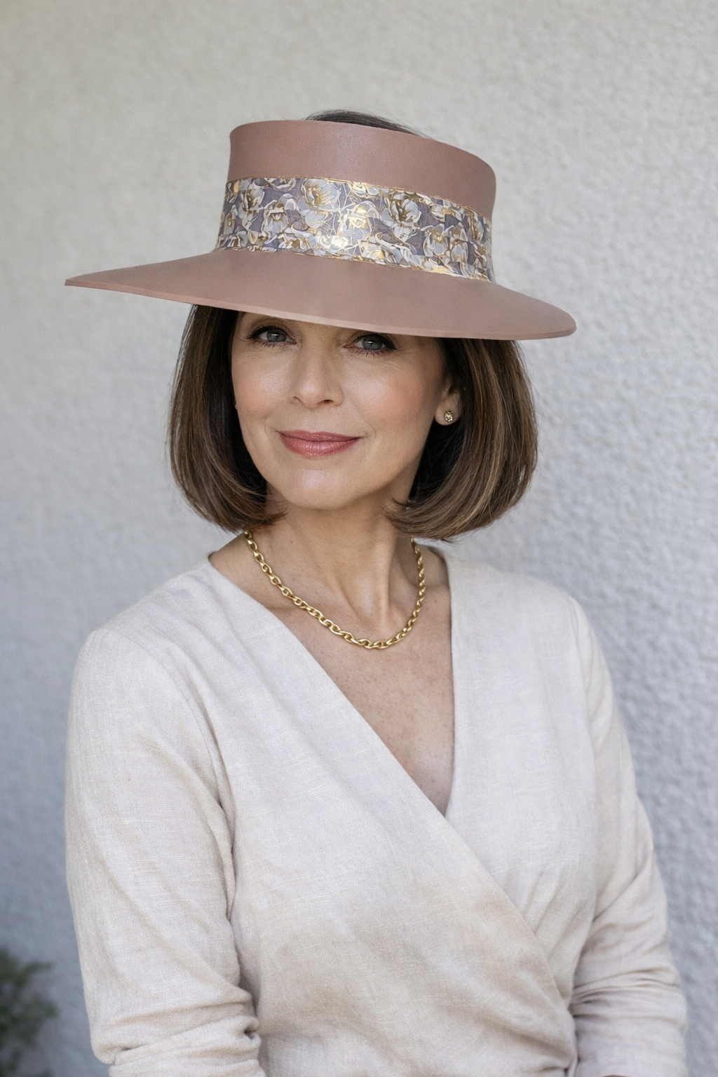 Woman wearing a wide-brimmed hat with decorative band against a plain background