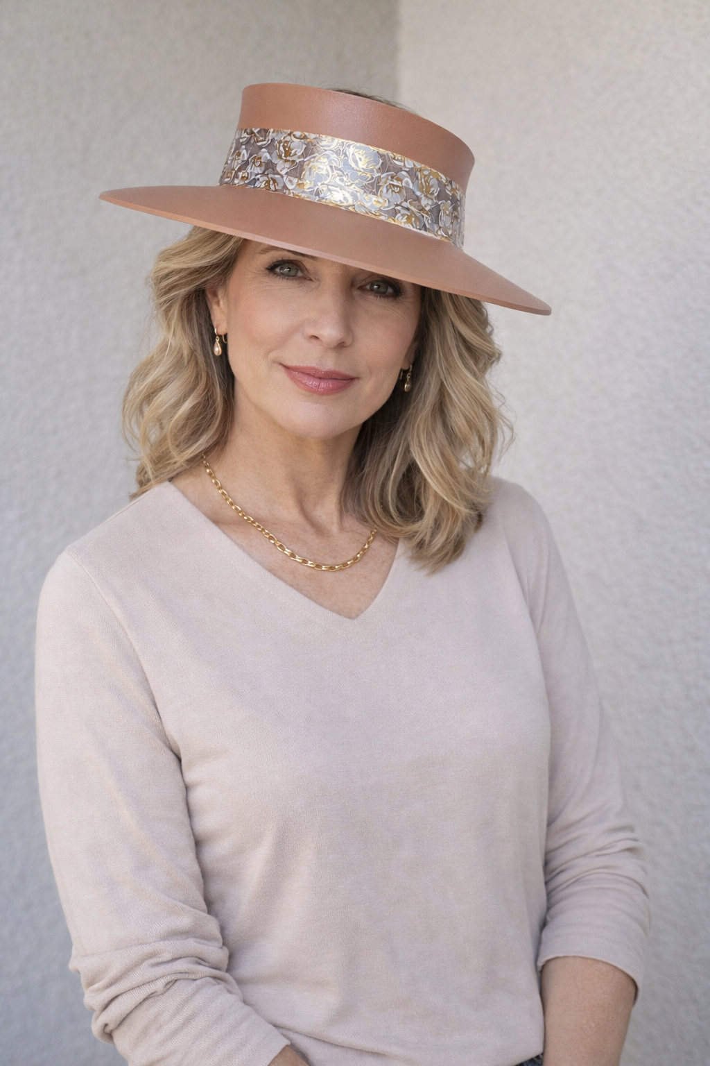 Woman wearing a wide-brimmed hat with a decorative band against a plain background