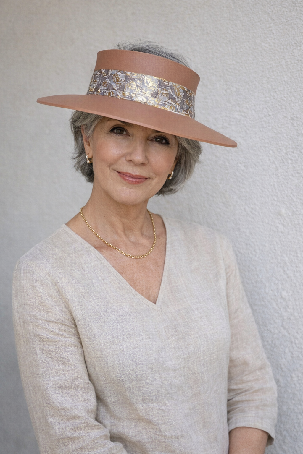 Woman wearing a wide-brimmed hat with a decorative band against a plain background