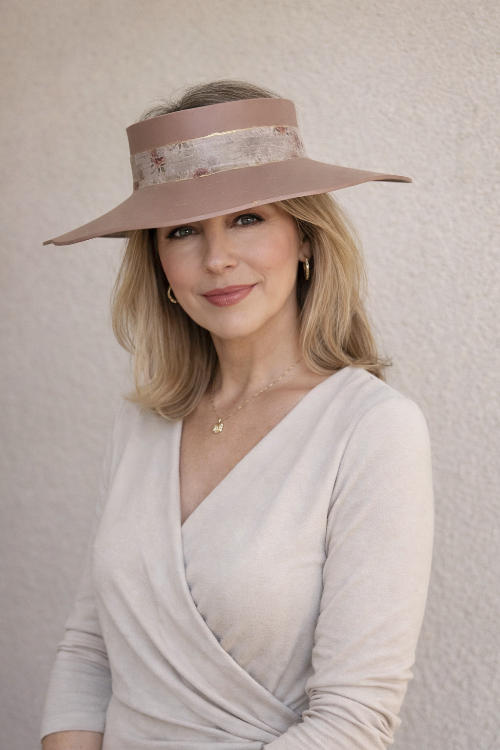 Woman wearing a beige visor hat with decorative band against a neutral background
