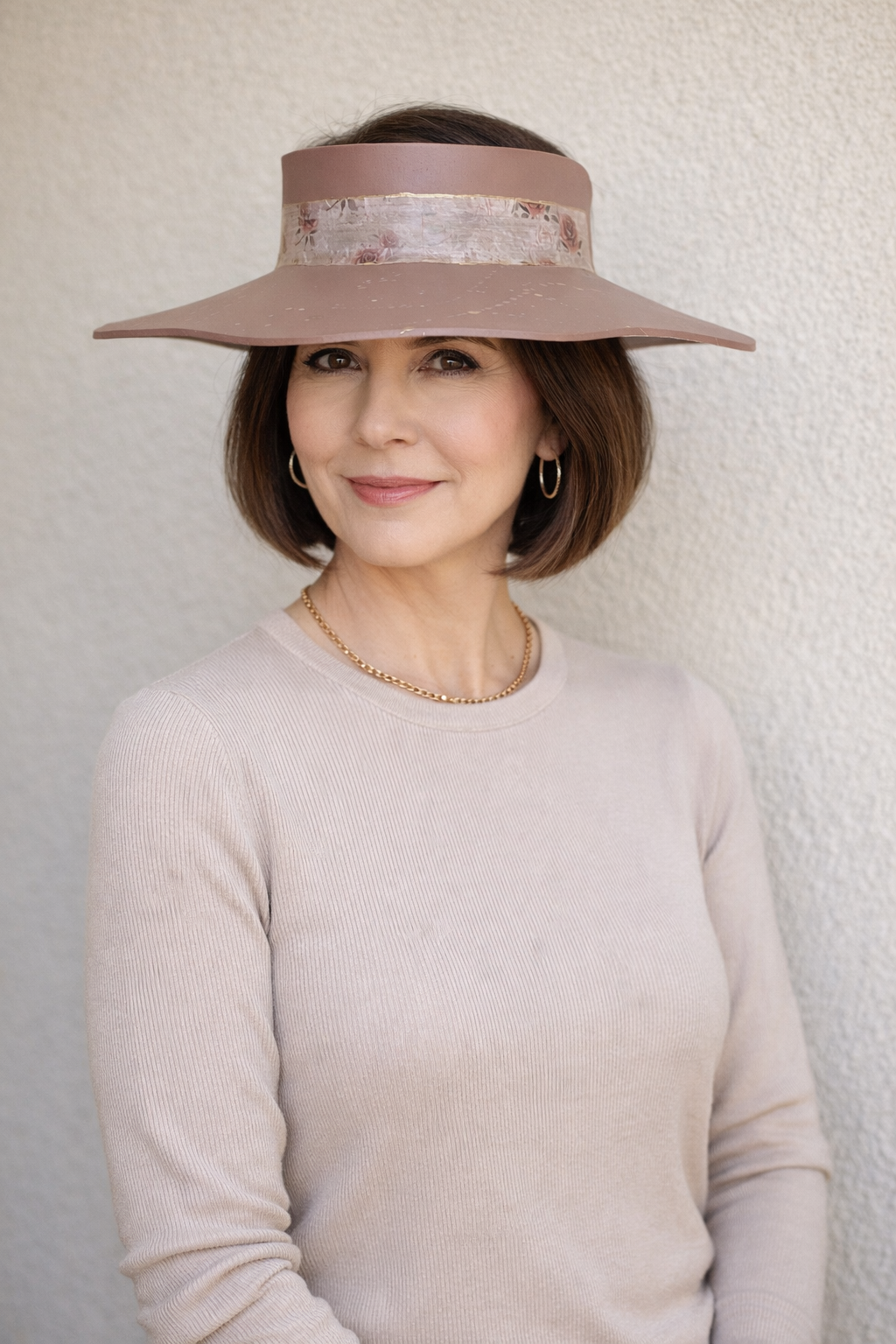 Woman wearing a wide-brimmed hat against a plain background