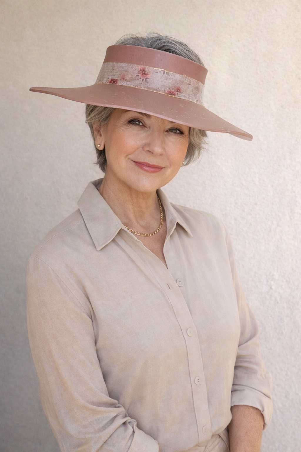 Woman wearing a wide-brimmed hat with floral details against a plain background