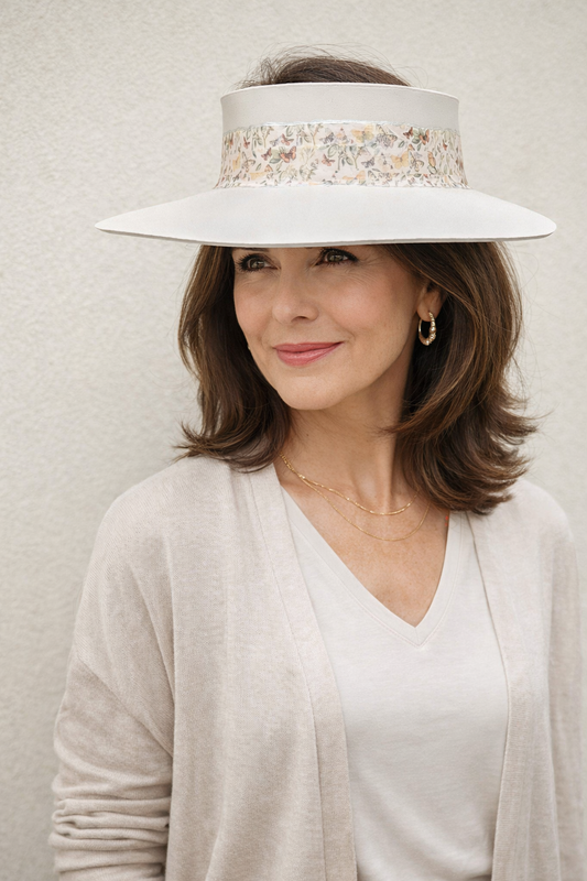 Woman wearing a wide-brimmed hat with a decorative band against a neutral background