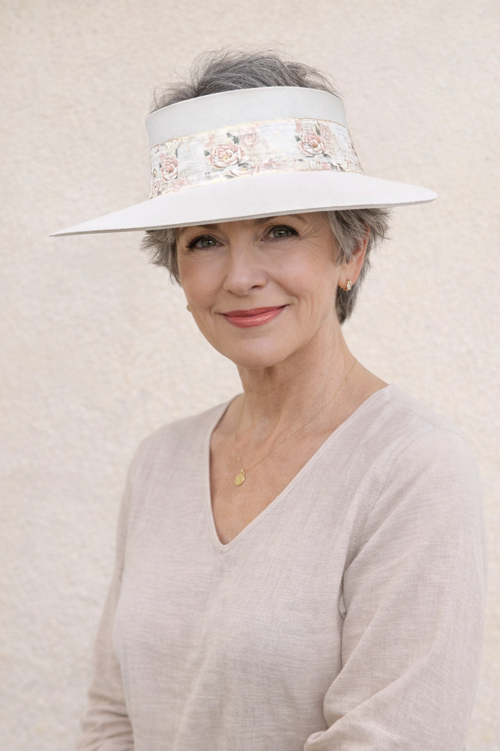 Woman wearing a white visor with floral patterns against a beige background