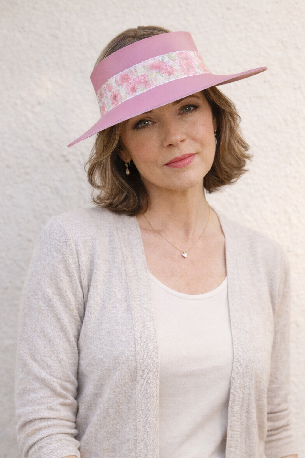 Woman wearing a pink visor with floral pattern against a light background