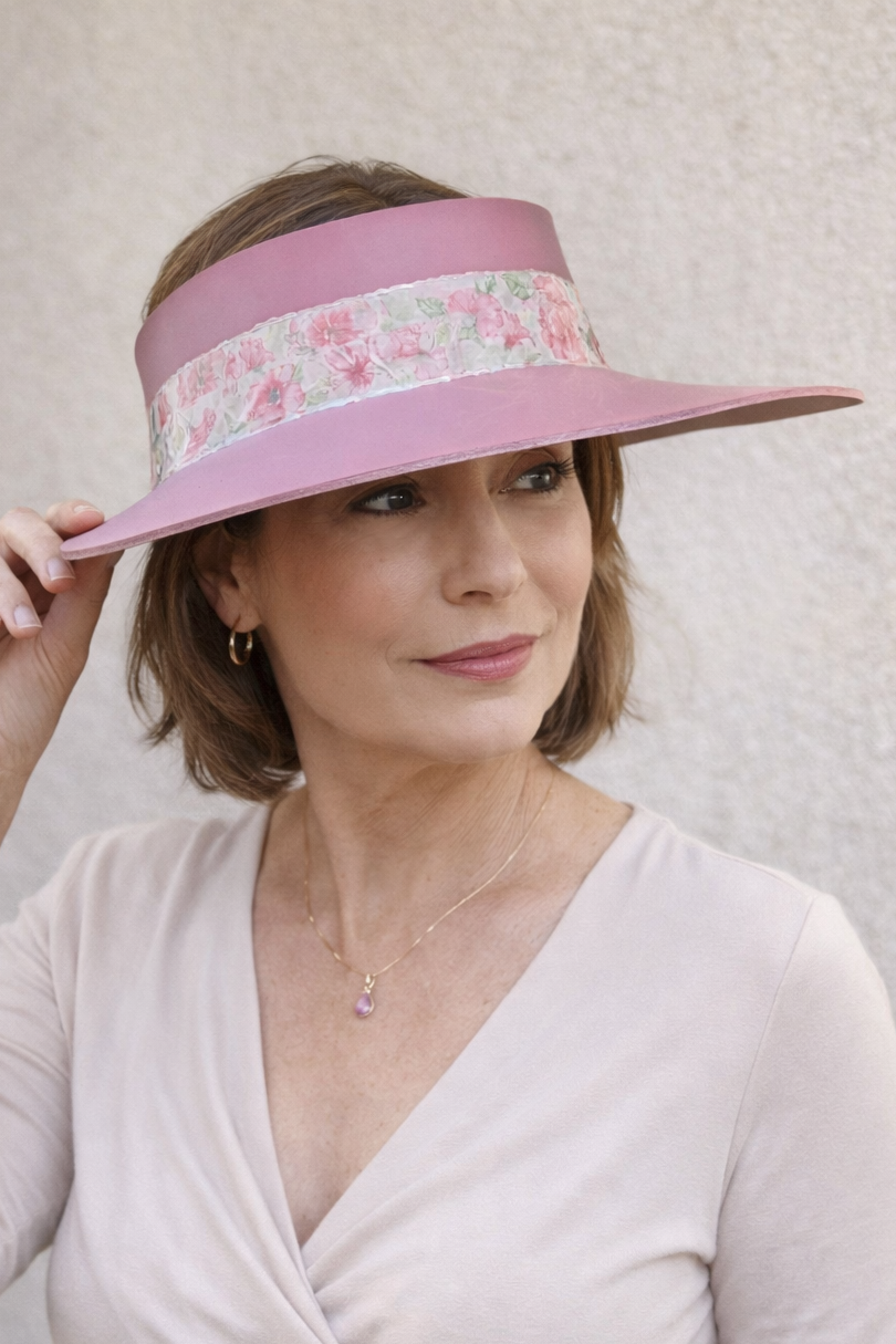Woman wearing a pink visor with floral band against a light background