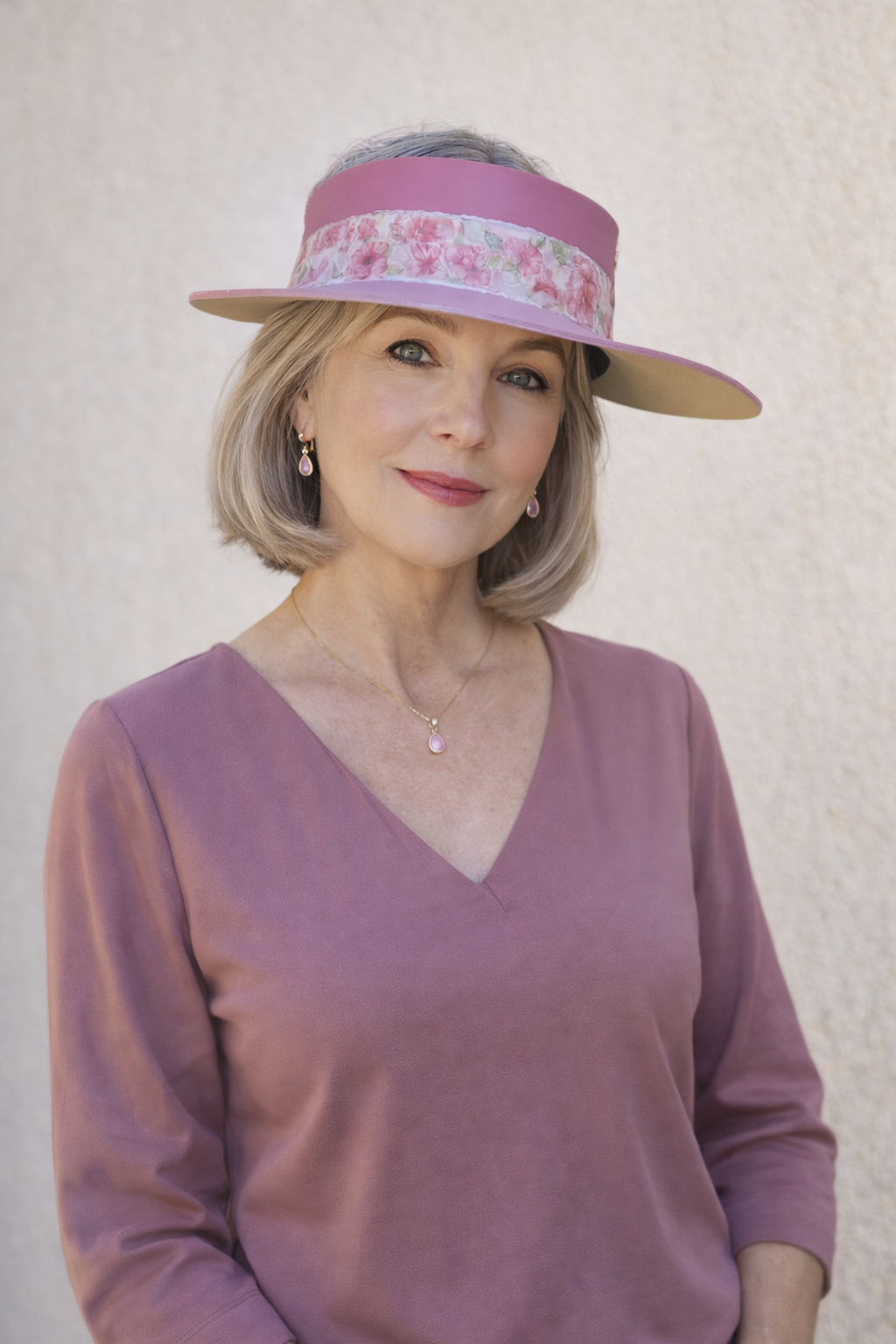 Woman wearing a pink visor and purple top against a light background