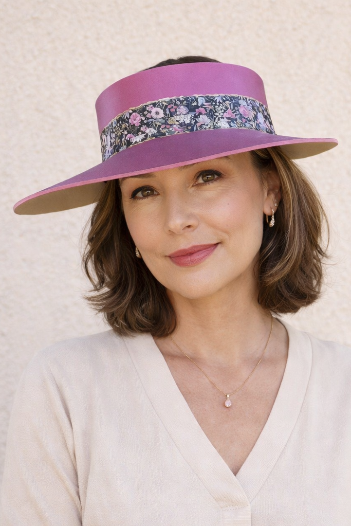 Woman wearing a wide-brimmed purple hat with floral band against a neutral background