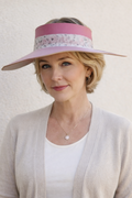 Woman wearing a wide-brimmed hat with a pink band against a light background