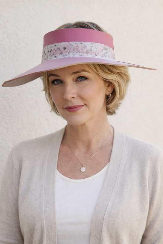 Woman wearing a wide-brimmed hat with a pink band against a light background