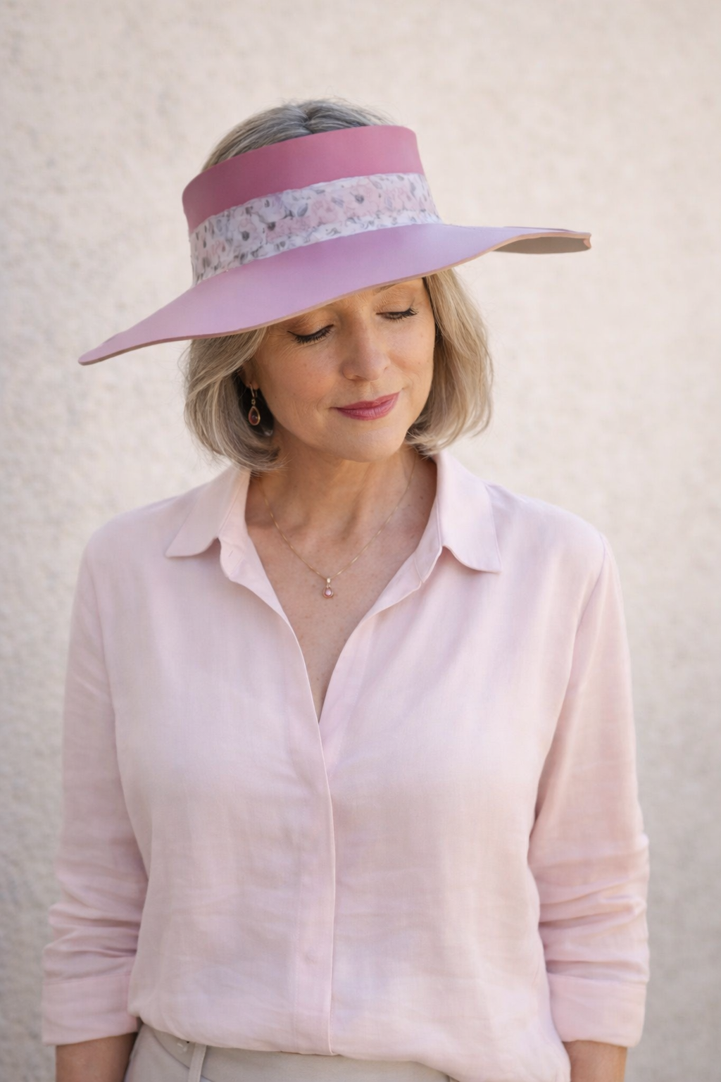 Woman wearing a pink visor and light pink shirt against a beige background