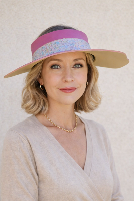 Woman wearing a wide-brimmed hat with colorful bands against a plain background