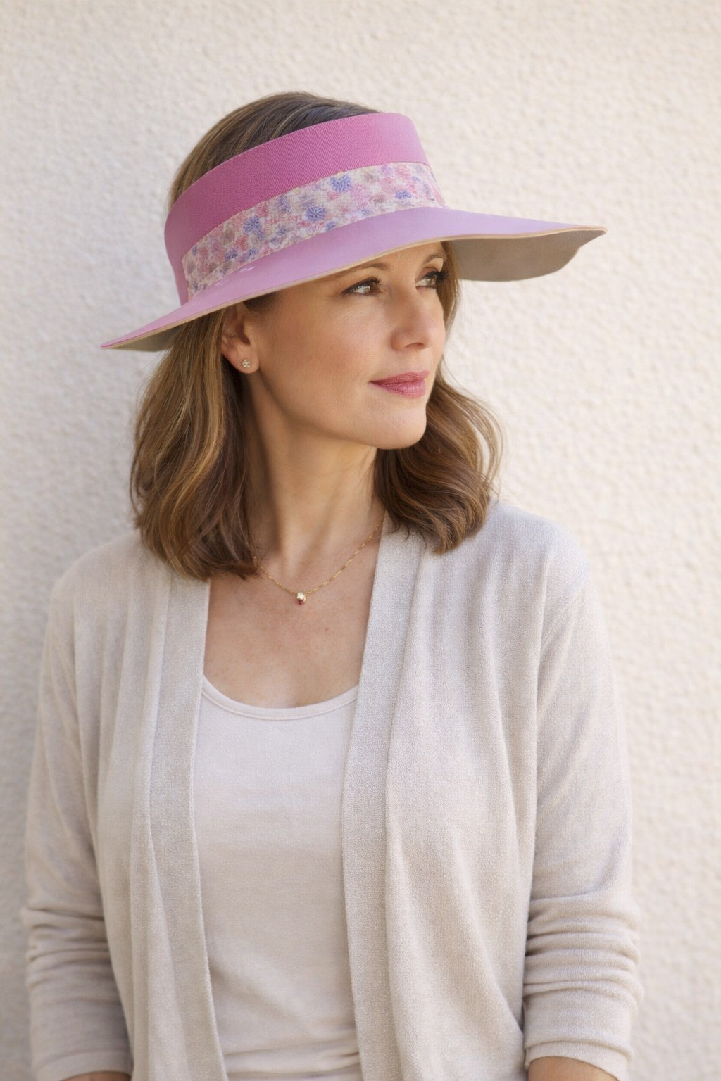 Woman wearing a pink visor with floral band against a white background