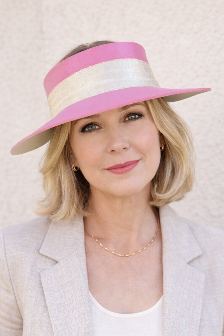 Woman wearing a pink and white visor against a light background