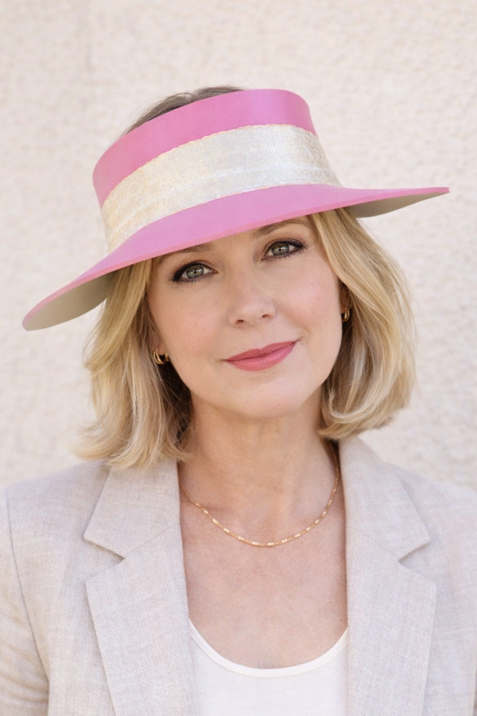 Woman wearing a pink and white visor against a light background