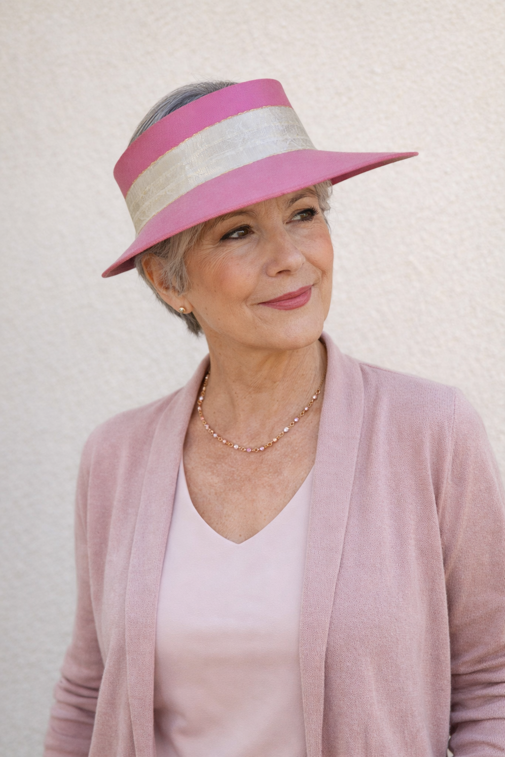 Woman wearing a pink and gray hat against a plain background