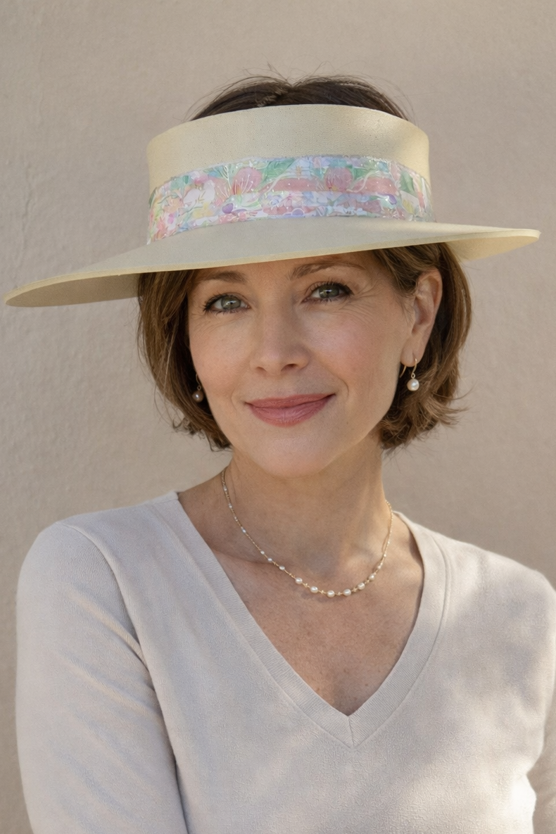 Woman wearing a wide-brimmed hat with a colorful band against a plain background