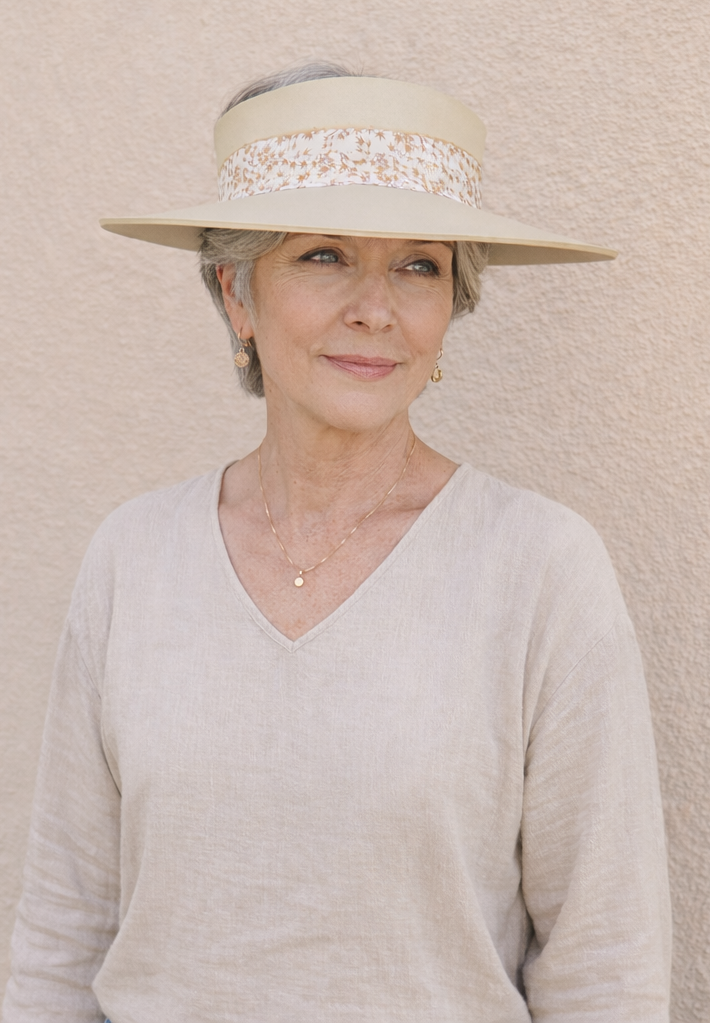 Woman wearing a beige hat with a pearl band against a beige wall