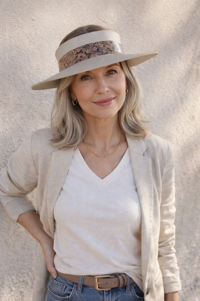 Woman wearing a wide-brimmed hat with a floral band against a neutral background